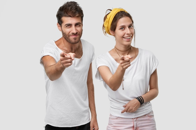 Photo of handsome man and European woman point  with both index fingers, make bang gesture, choose something