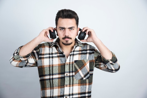 Free photo photo of handsome man with headphones standing and looking over white wall.