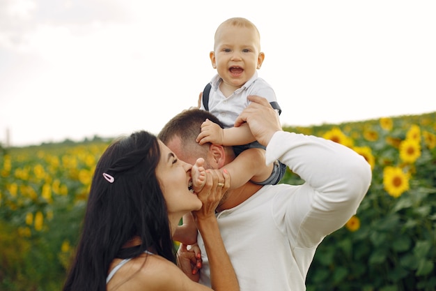 Photo of happy family. Parents and daughter. Family together in sunflower field. Man in a white shirt.