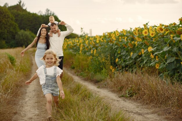 Photo of happy family. Parents and daughter. Family together in sunflower field. Man in a white shirt.