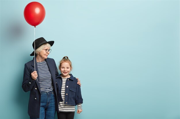 Photo of happy grandmother and granddaughter stand closely