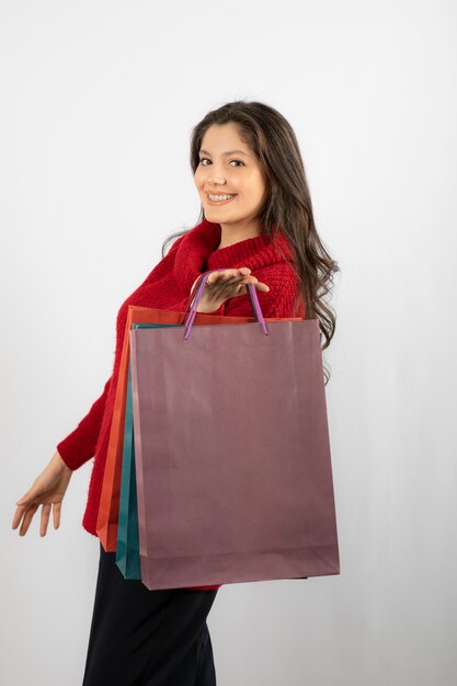 Фотография счастливой дамы, показывающей свои красочные хозяйственные сумки.