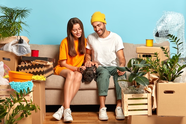 Photo of happy young couple sitting on the couch surrounded by boxes