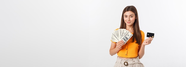 Photo of happy young woman standing isolated over grey background looking aside holding money and cr