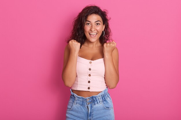 Photo of happy young woman with beautiful dark wawy hair screaming, wearing stylish outfit