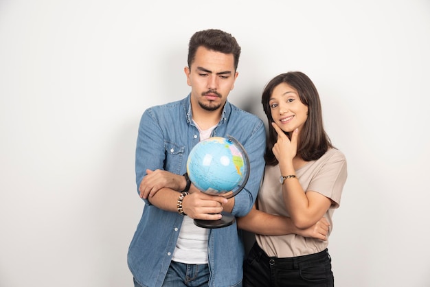 Photo of man and woman holding earth globe over white.