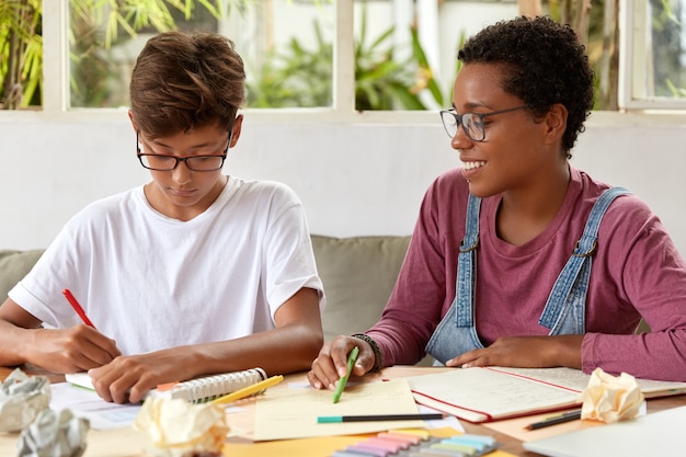 Photo of multiethnic women write down notes for making diploma paper