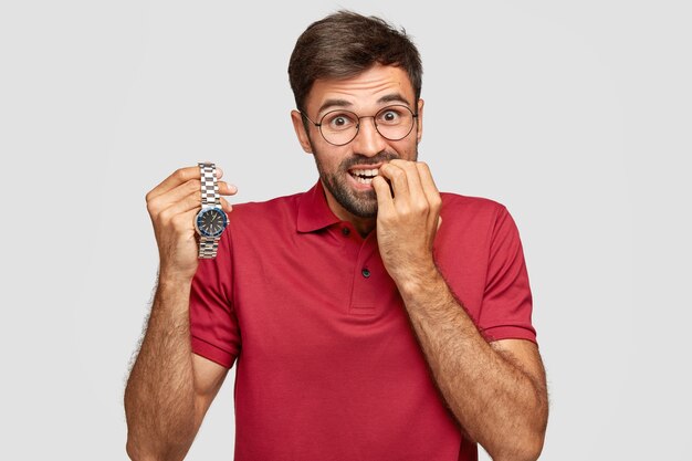 Photo of nervous man bites finger nails, has anxious expression