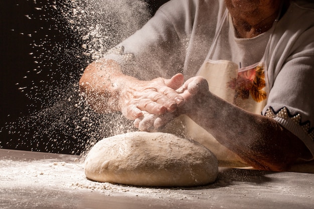 小麦粉​の​スプラッシュ​と​小麦粉​と​女性​の​手​の​写真​。​調理​パン​。​生地​を​こねる​。​暗い​背景​に​分離されました​。​テキスト用​の​空き​スペース