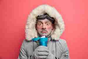 Бесплатное фото Фотография шокированного, смущенного человека, дрожащего от холода, проводит много времени на улице в морозную погоду, пьет горячий чай, держит термос, носит одежду для зимних видов спорта.