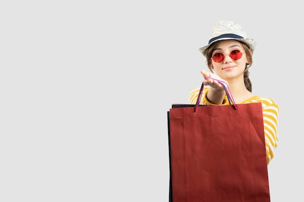 ショッピングバッグを保持しているサングラスの若いブルネットの女性の写真。高品質の写真