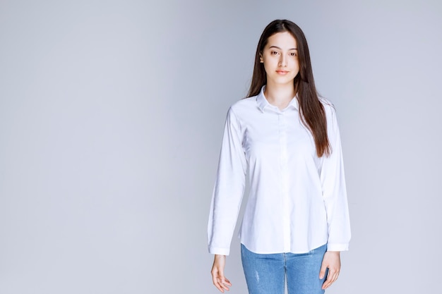 壁に立っている白いシャツを着た若い女性の写真。高品質の写真