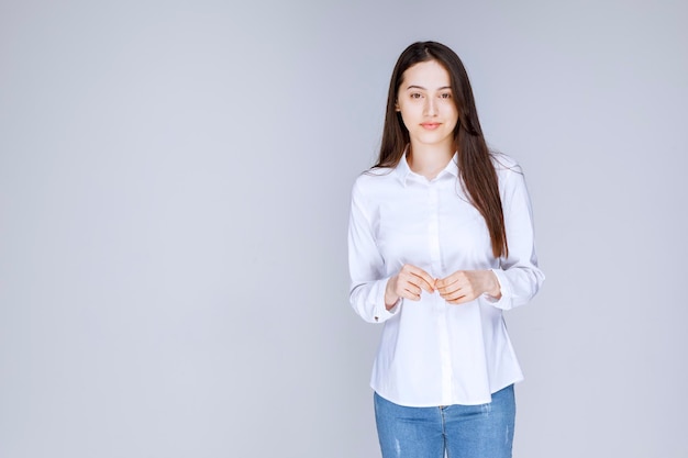 壁に立っている白いシャツを着た若い女性の写真。高品質の写真