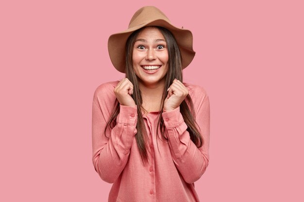 Photo of overjoyed European woman keeps hands together