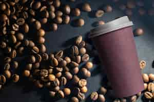 Free photo photo of a paper coffee cup with a mixture of arabica and robusta beans in the background.