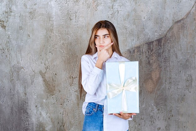 Photo of a pensive model with long hair holding big present