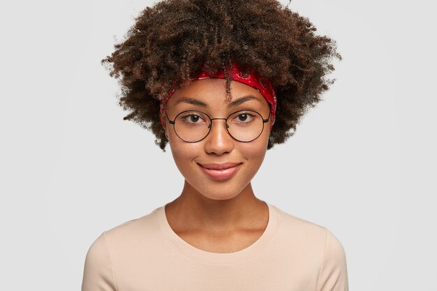 Photo of pleasant looking cheerful dark skinned woman in round eyewear