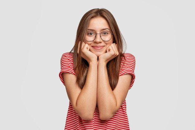 Photo of pleasant looking delighted dark haired woman has friendly expression