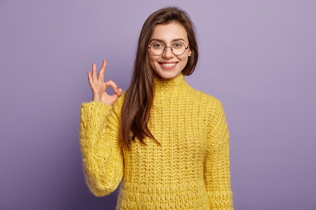 Photo of positive European female model makes okay gesture, agrees with nice idea