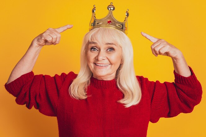 photo of positive old woman having point finger golden crown