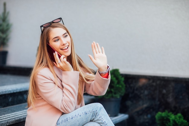 かわいい女の子の写真は、通りで彼女の時間を過ごし、彼女の電話で話します。誰かと会う。