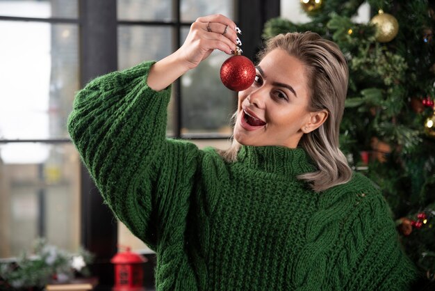 Photo of pretty lady holding a Christmas ball wearing green knitted sweater