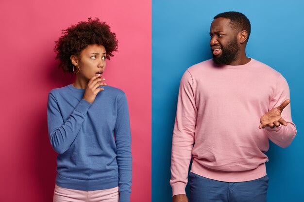 Photo of puzzled Afro American woman and man have displeased expressions, discuss something unpleasant, got bad news