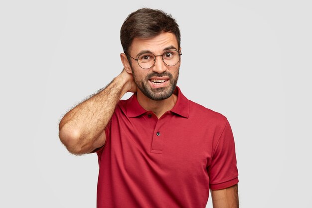 Photo of puzzled man with stubble, scratches head
