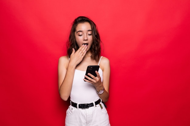 Foto di donna soddisfatta utilizzando il telefono cellulare con gioia oltre il muro rosso