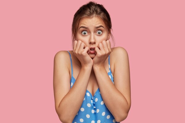 Photo of scared woman keeps hands near mouth