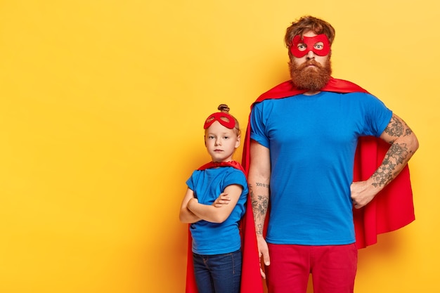 Free photo photo of serious bearded man and self confident little child stands near with crossed arms