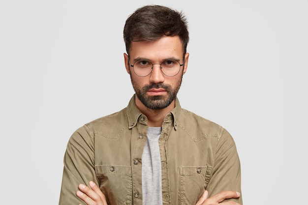 Free photo photo of serious handsome guy posing against the white wall