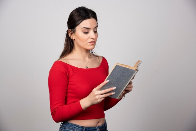 Photo of a serious woman reading a book and holding a pencil.