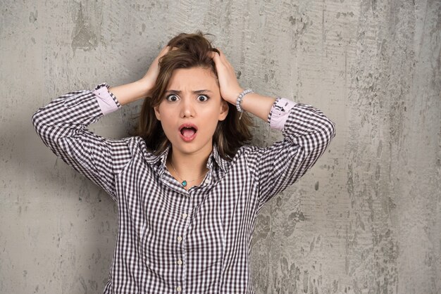 Photo of shocked woman in plaid shirt holding her head