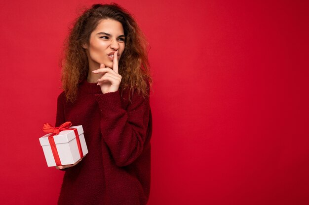 Photo shot of beautiful positive emotional young brunette curly woman isolated over red background