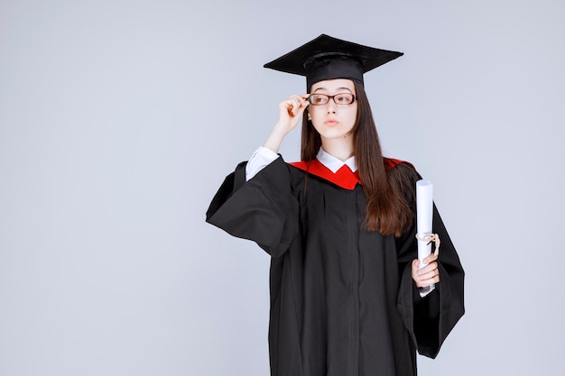 Photo of smart student in glasses celebrating graduation with diploma. High quality photo