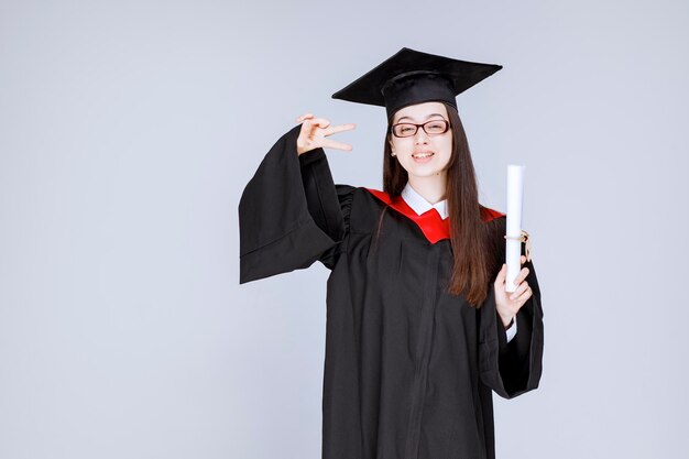 Photo of smart student in glasses celebrating graduation with diploma. High quality photo