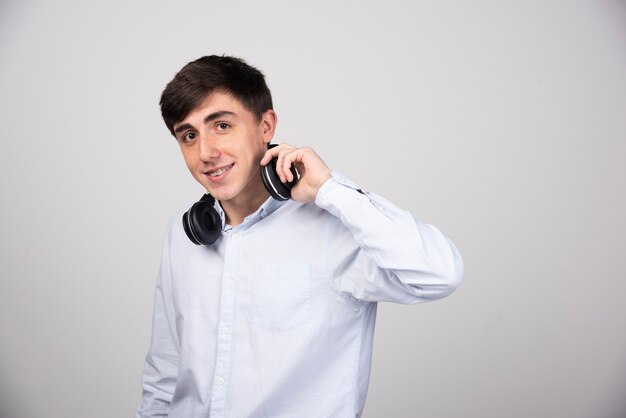 Photo of a smiling  guy model standing in wireless headphones and looking at camera