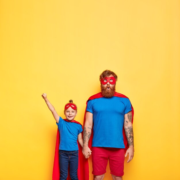 photo of suprirsed father holds hand of little daughter who makes flying gesture