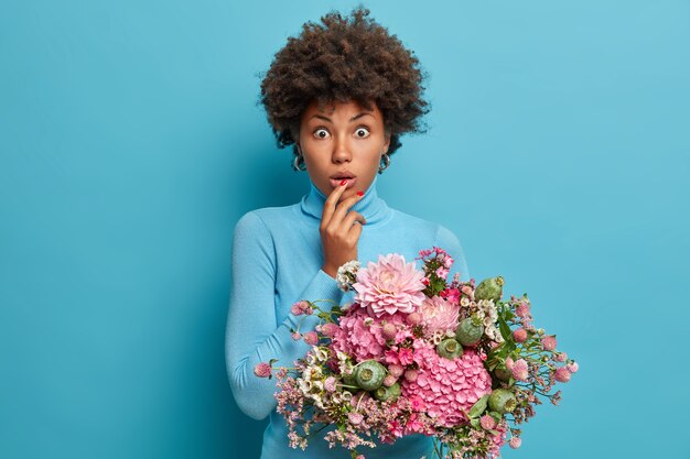 Photo of surprised dark skinned woman gets flowers