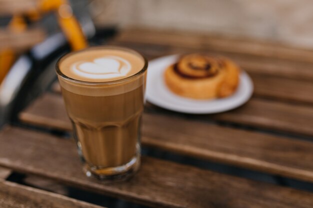 Photo of tasty cake with glass of cappuccino in focus