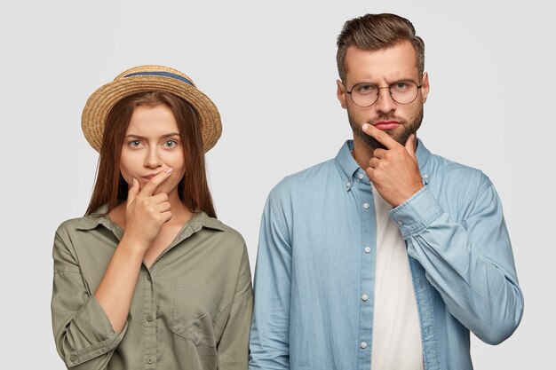 Photo of thoughtful confused female and male coworkers keep hands on chins