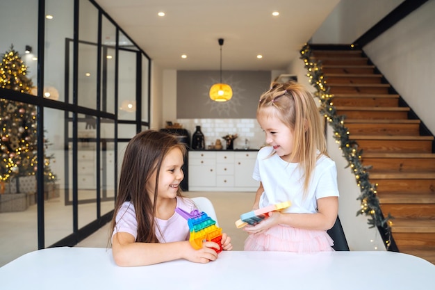 Photo of two little girls playing at the table on the camera indoors