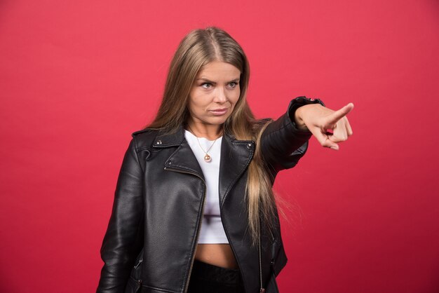 Photo of woman in leather jacket pointing away and giving direction