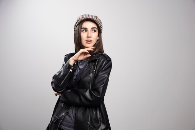 黒革のジャケットとキャップで目をそらしている女性の写真。
