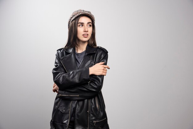 photo of a woman looking away in black leather jacket and cap.
