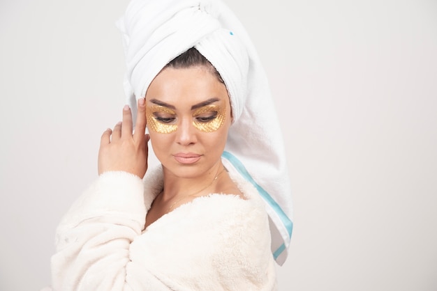 Photo of a woman looking down with hydrogel eye patches .