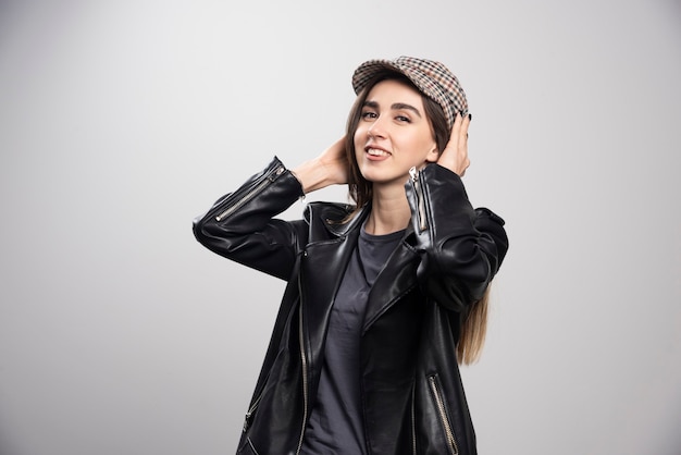 검은 가죽 재킷과 모자에 포즈를 취하는 여자의 사진.