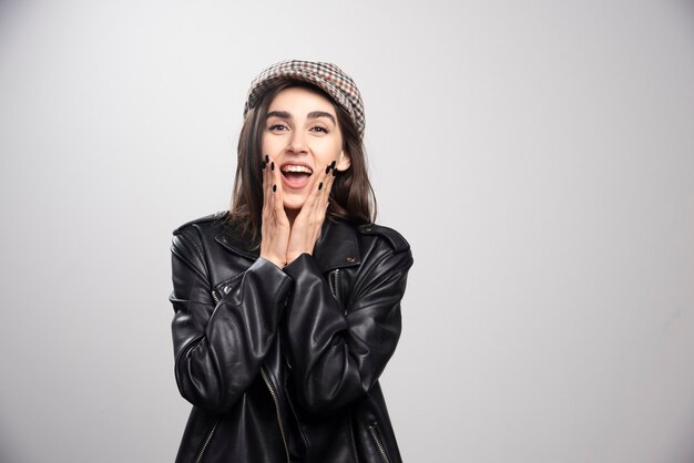 Photo of a woman posing in black leather jacket and cap.