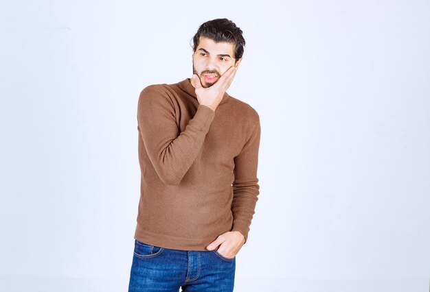 Photo of a young attractive man model standing and posing over white wall. High quality photo